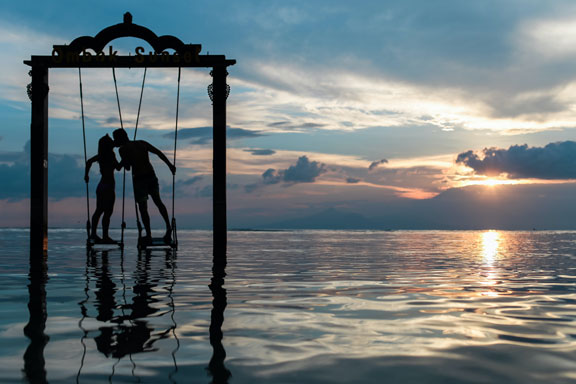 A couple kissing in the sunset on swings