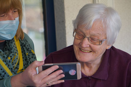 Sharing cell phone with elderly woman.